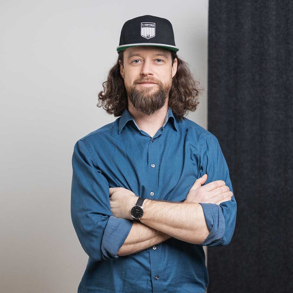 Portrait von Christoph Schubert, Mitgründer von Resolyze, mit Cap, blauem Hemd und verschränkten Armen